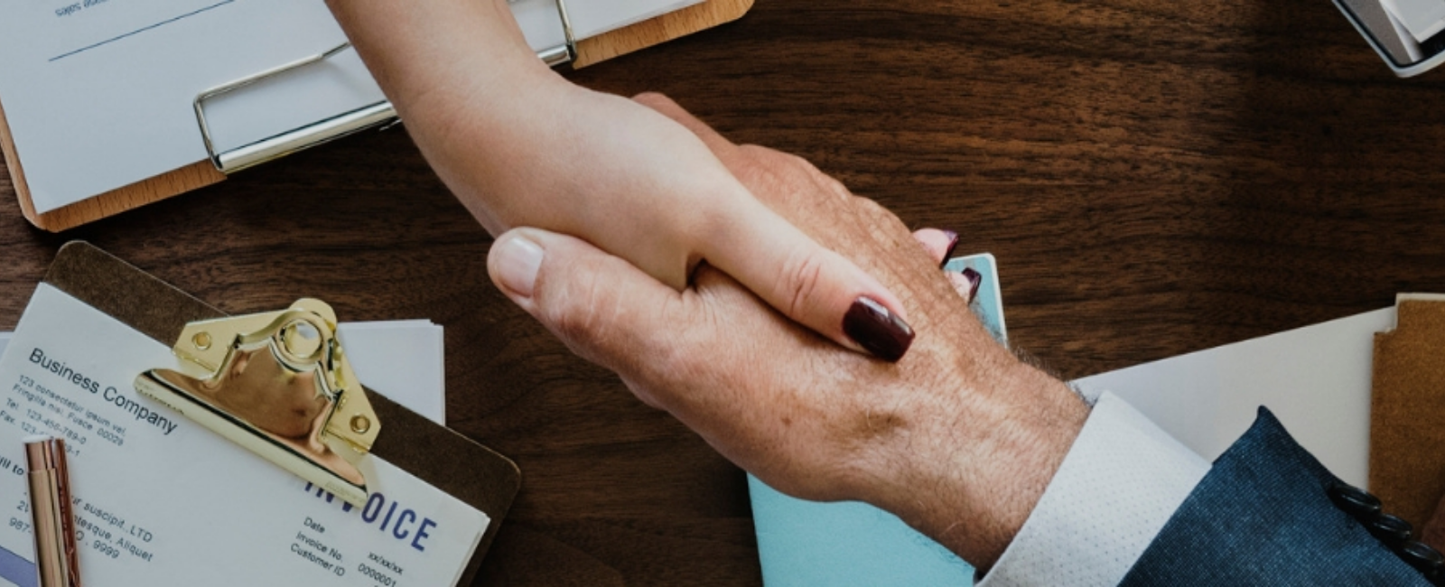 two people shaking hands over business plans